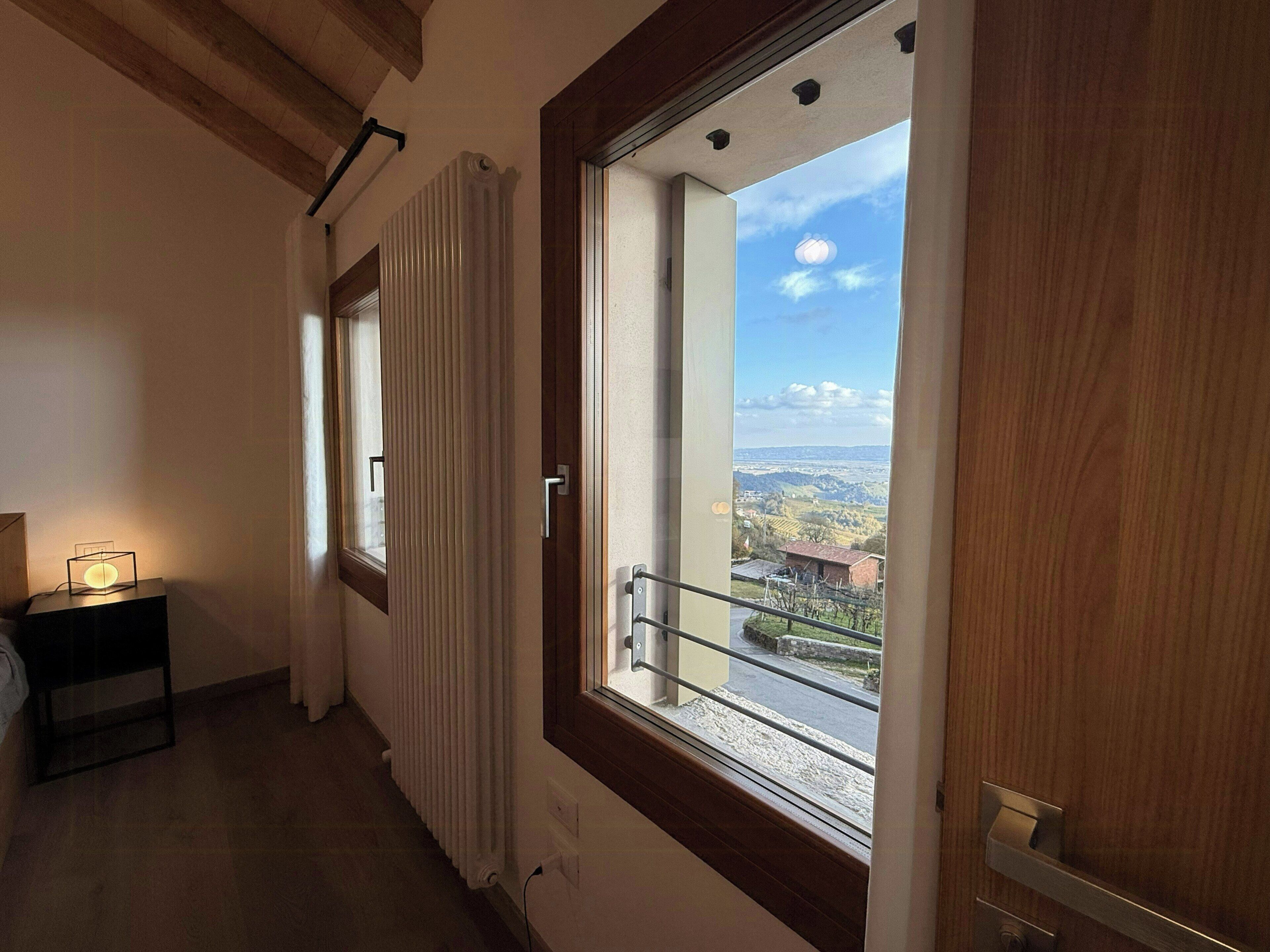 Une pièce avec une grande fenêtre, un radiateur et une petite table avec une lampe.