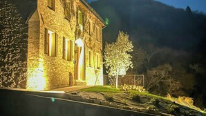 A stone building with a well-lit entrance and a view of a mountain in the background.