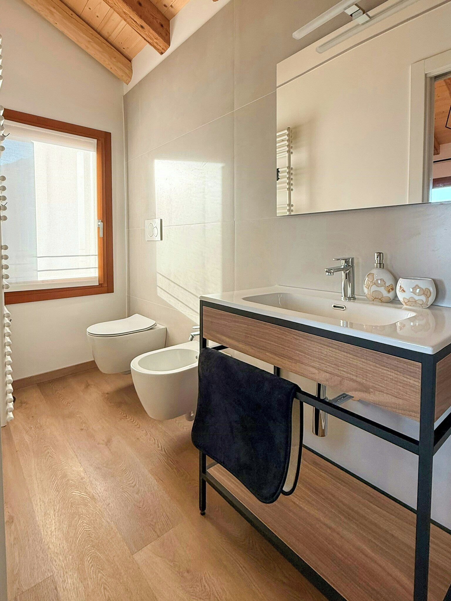 Ein modernes Badezimmer mit einem Holzkosmetikschrank, einem großen Spiegel, einer Toilette und einem Bidet.