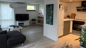 Uma sala de estar moderna com televisão de tela plana, um sofá e um espaço de jantar com mesa e cadeiras.