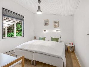 A bedroom with a bed, a bedside table, a red alarm clock, and a window with blinds. - "Eike" -  from the sea by Interhome (Hadsund)