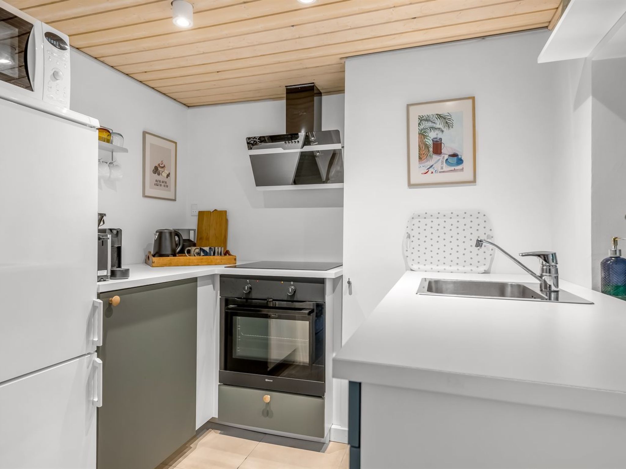 Een compacte keuken met een inbouwoven, een magnetron en een spoelbak met een moderne kraan.