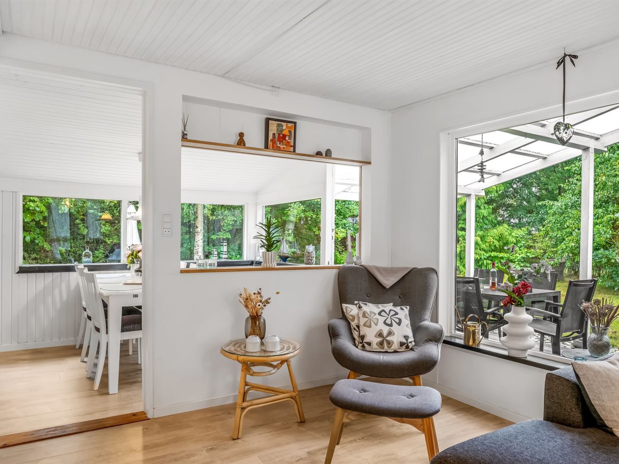 A modern living room with a large window, a dining area, and a cozy seating area.