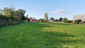 A grassy field with a red barn and several houses in the background.