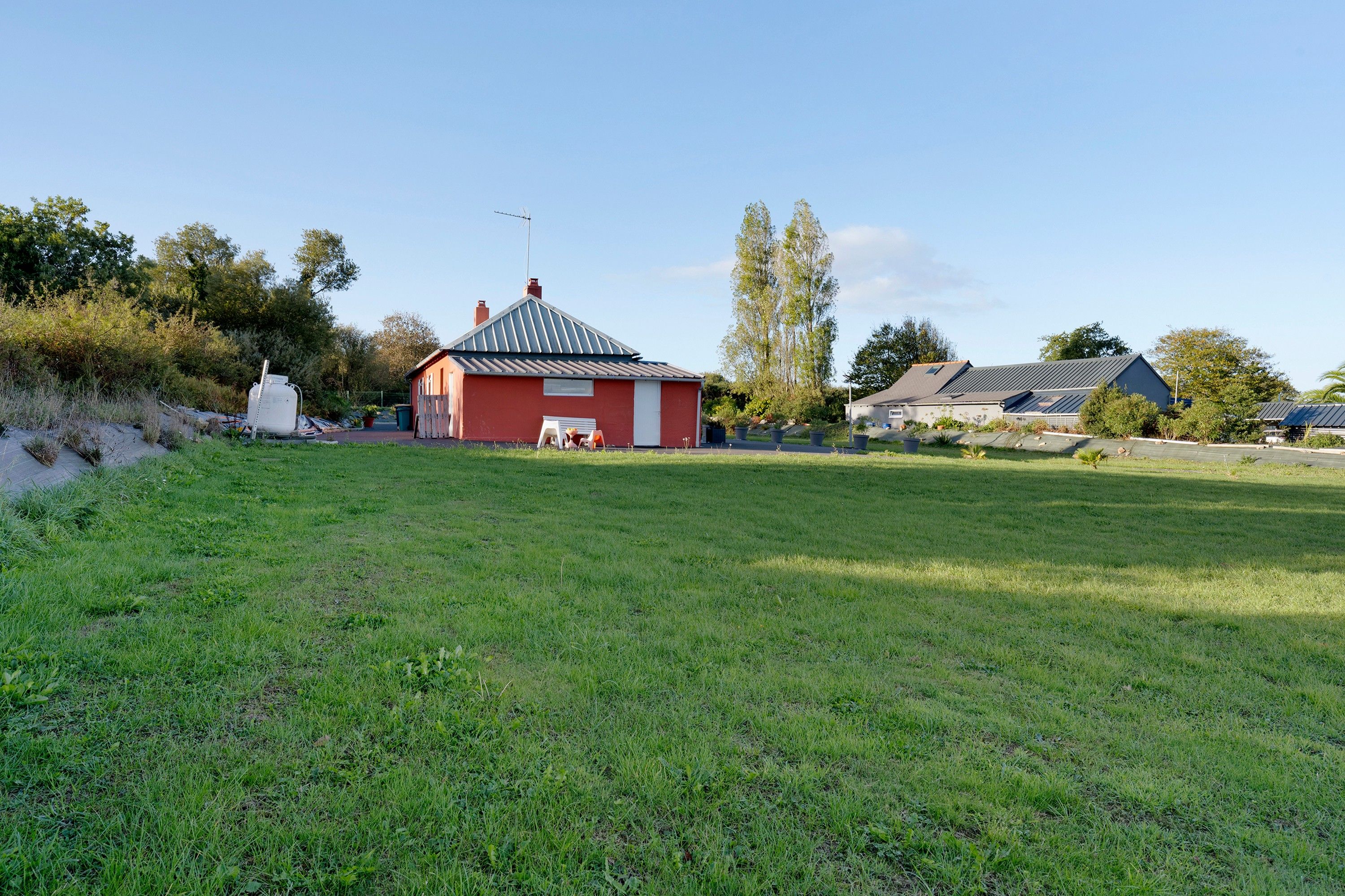 A rural landscape with a red barn, a green field, and a few residential buildings.