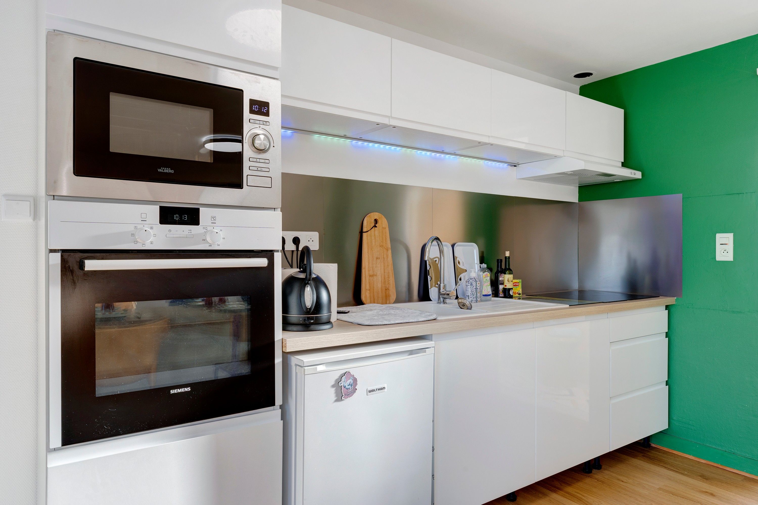 Una cocina moderna con microondas, horno y un refrigerador pequeño.
