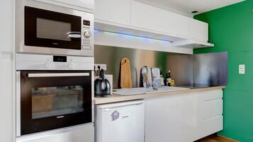 Una cocina moderna con microondas, horno y un refrigerador pequeño.