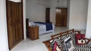 A room with a bed, a wooden wardrobe, a wooden bench, and a ceiling fan.