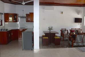 A kitchen with wooden cabinets, a refrigerator, and a dining area with a table and chairs.