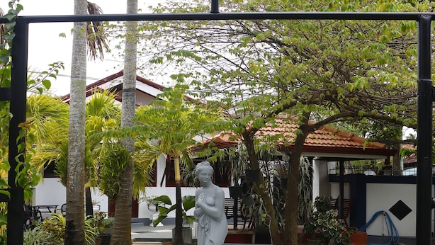 A garden with a statue, a lawn, and a building in the background.