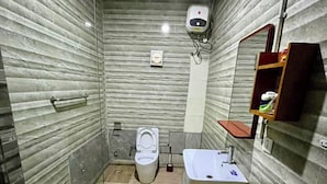 Uma casa de banho compacta com cabine de chuveiro em vidro, sanita e lavatório com espelho em cima.