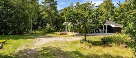 Ein ländliches Anwesen mit einem Kiesweg, einer Holzterrasse und einem Gebäude mit Ziegeldach.