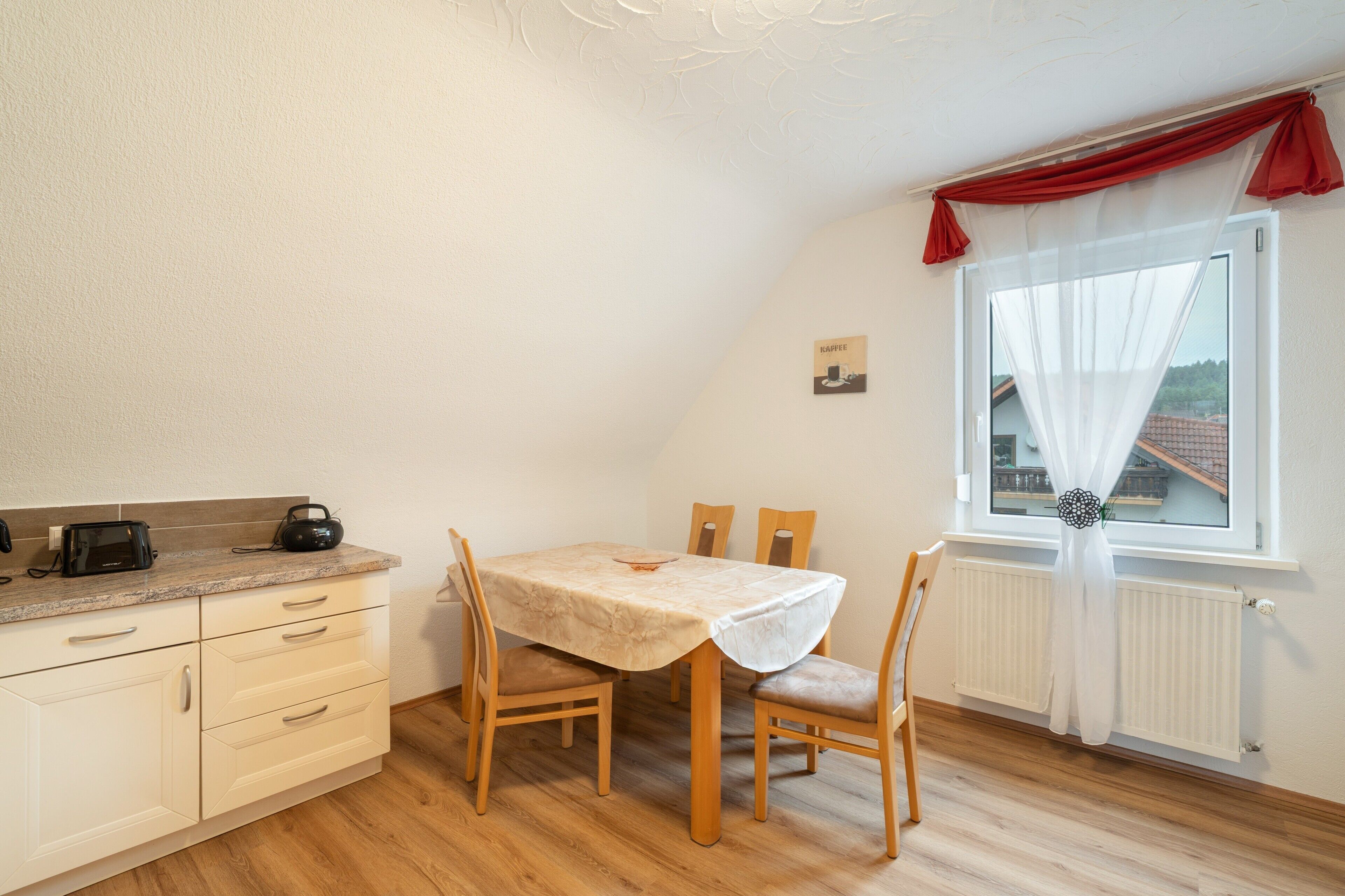 Eine kleine, gemütliche Küche mit Tisch und Stühlen, einem Toaster und einem Radio.