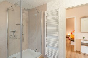 A modern bathroom with a glass shower enclosure, a white towel rack, and a visible bathroom counter.