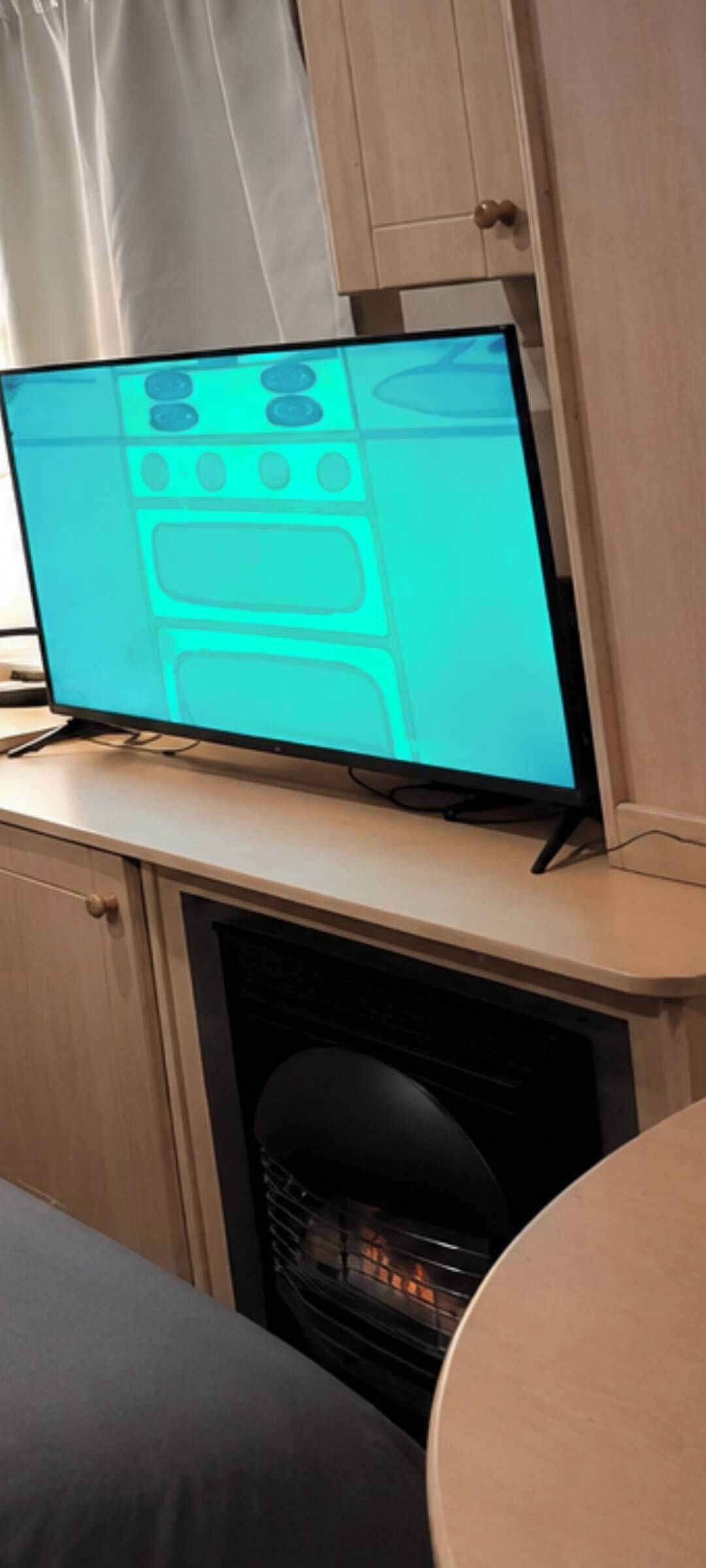 Un televisor de pantalla plana sobre un mueble de madera con un diseño de estufa en la pantalla.