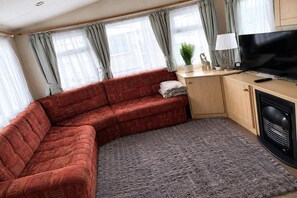 A living room with a red sofa, a grey rug, a television, and a small table with a lamp.