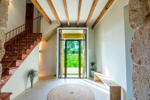 A modern interior with a stone wall, a wooden staircase, a large glass door leading to a garden, and a round rug on the floor. - Fantastic villa with private pool in Santa Margalida (Santa Margalida)