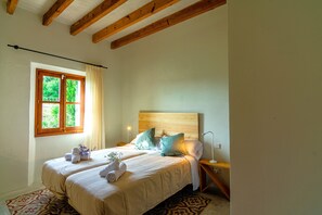 A bedroom with a wooden headboard, a bed with white bedding, a nightstand with a lamp, and a window with curtains. - Fantastic villa with private pool in Santa Margalida (Santa Margalida)