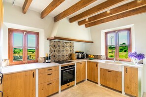 A modern kitchen with wooden cabinets, a built-in oven, and a view through the windows. - Fantastic villa with private pool in Santa Margalida (Santa Margalida)
