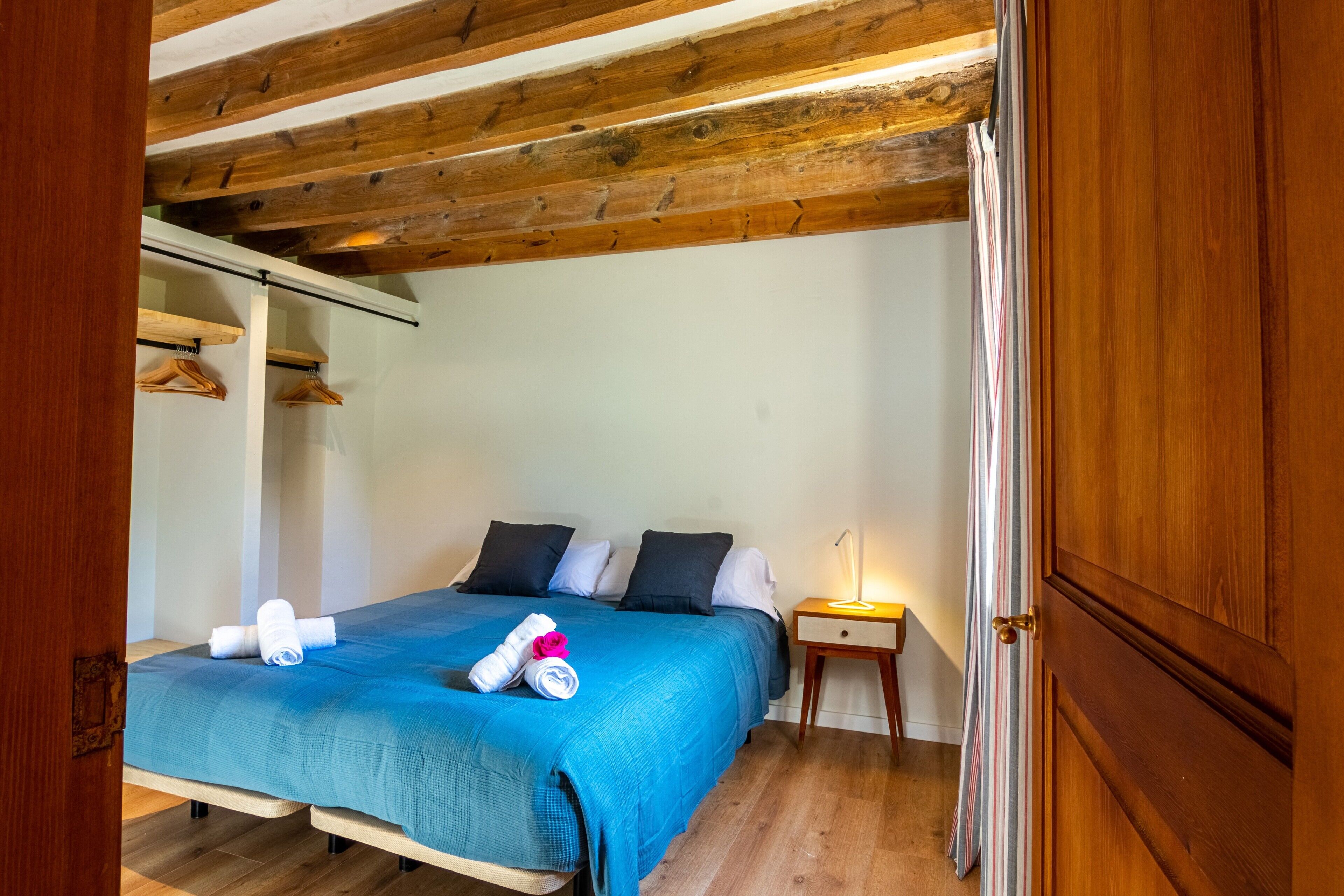 Un dormitorio con cama, almohadas, una mesita de noche y una puerta.