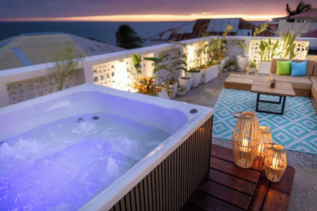 Une terrasse sur le toit avec un jacuzzi, des sièges d’extérieur et des plantes en pot.