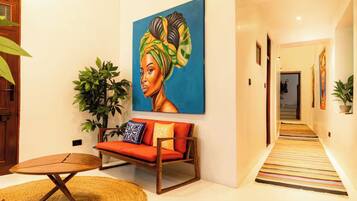 A hallway with a sofa, a painting, and a plant.