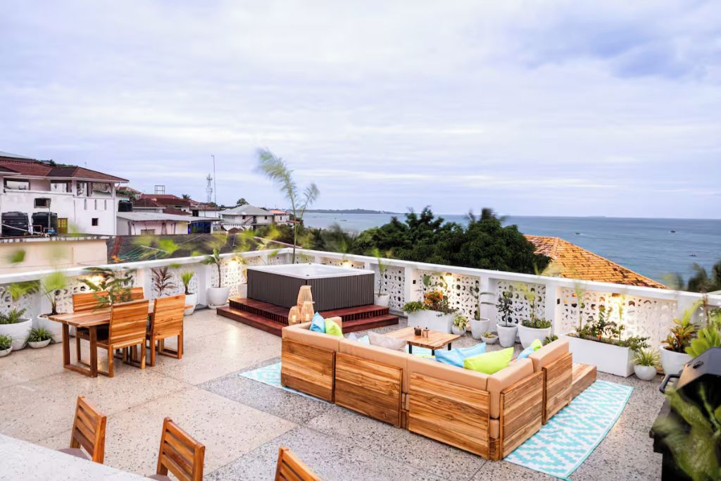 A rooftop terrace with a seating area, a hot tub, and a view of the sea.