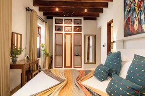 Une chambre d’hôtel avec un lit, un canapé, un bureau et un miroir. Il y a une fenêtre avec des rideaux et un tableau au mur.