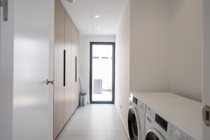 Une buanderie équipée d’un lave-linge, d’un sèche-linge et d’une fenêtre donnant sur un espace extérieur.