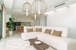 A modern living room with a sectional sofa, a wooden coffee table, and a large potted plant. - Moana 4 - Luxury Home with Private Pool (Benalmádena)