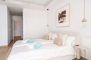 Une chambre d’hôtel comprenant un lit, une table de chevet, une œuvre d’art accrochée au mur et une porte donnant sur une autre pièce.