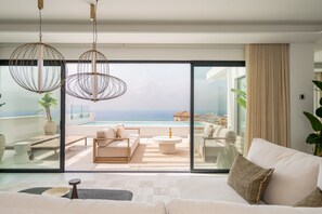 A modern living room with a large glass door leading to a balcony with a pool and ocean view. - Moana 4 - Luxury Home with Private Pool (Benalmádena)