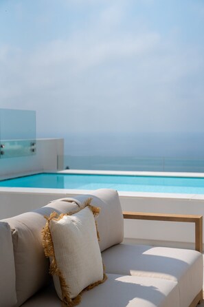 Un espace aménagé avec des sièges, situé au bord de la piscine et offrant une vue sur l’océan.