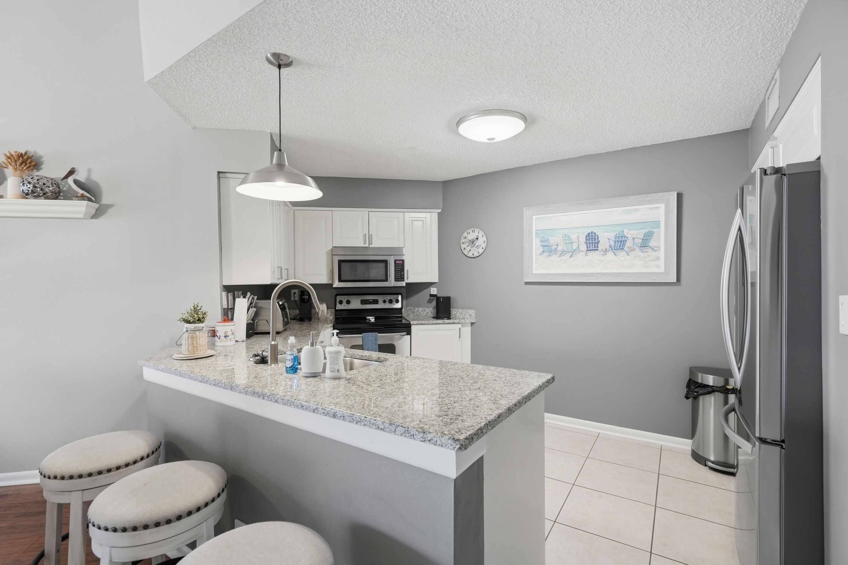 A modern kitchen with granite countertops, stainless steel appliances, and a central island with stools.