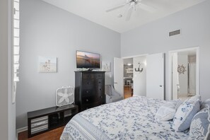 Ein Schlafzimmer mit einem Bett, einem Schminktisch, einem Fernseher und einem Deckenventilator.