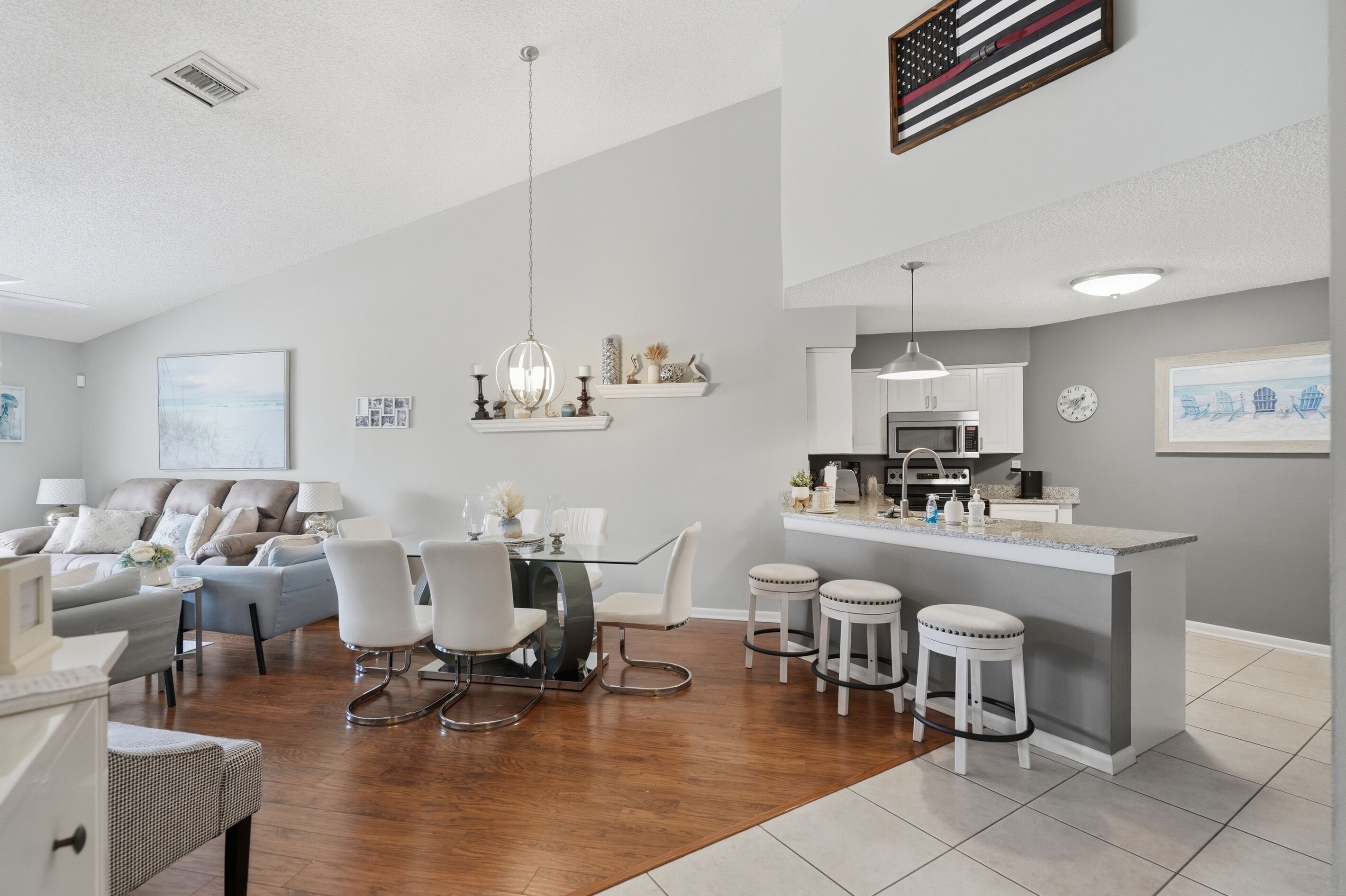 Une cuisine moderne dotée d’un îlot central, de meubles blancs et d’une hotte de cuisine en acier inoxydable.