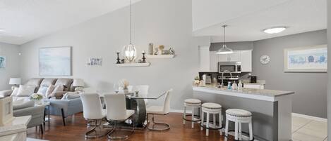 A modern kitchen with a central island, white cabinetry, and a stainless steel range hood.