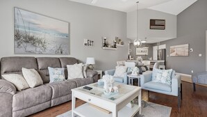 A modern living room with a grey sofa, a white coffee table, and a blue armchair.