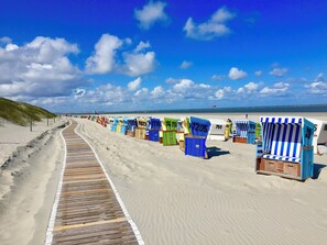 A beach with a wooden boardwalk and colorful beach chairs lined up along the sand. - Vrbo Property (Langeoog)