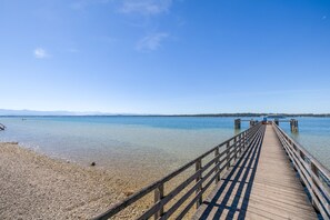 A wooden pier extending into calm water with clear skies.