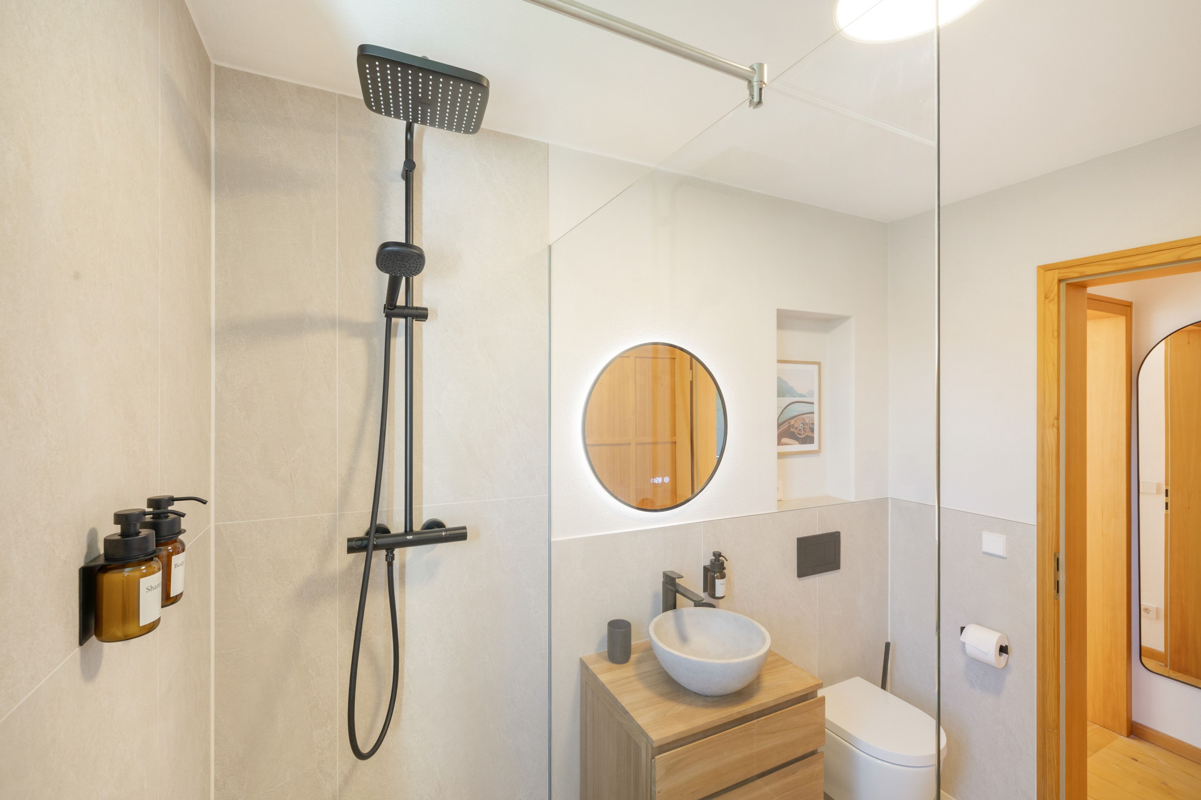 Ein modernes Badezimmer mit Dusche, Waschbecken, Toilette und Spiegel.