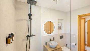 Ein modernes Badezimmer mit Dusche, Waschbecken, Toilette und Spiegel.