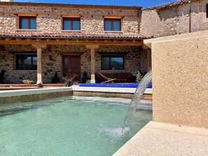Ein Gebäude aus Stein mit Pool, einer Holzterrasse und einem blau gefliesten Bereich.