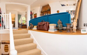 A staircase leading to a living area with a blue sofa, books, and decorative items. - 2-Bed Chelsea Flat | Balcony & River View (London)