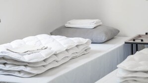 Une chambre minimaliste avec deux lits, chacun recouvert de linge de lit blanc.