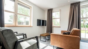 Un salon moderne avec un canapé, un fauteuil, une table basse et un téléviseur à écran plat.