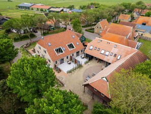 Zona residenziale con case dotate di tetti in tegole rosse, un cortile lastricato e verde circostante.