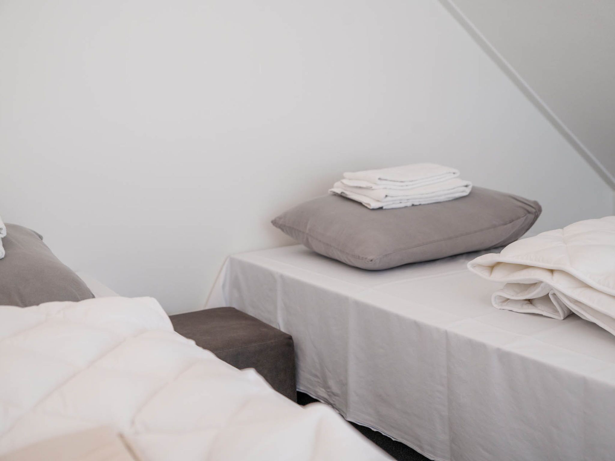 Ein Schlafzimmer mit zwei Betten, jedes mit einem Kopfkissen und einer zusammengeklappten Decke.