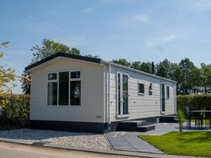 Ein eingeschossiges Mobilheim mit flachem Dach, großen Fenstern und einer Tür.