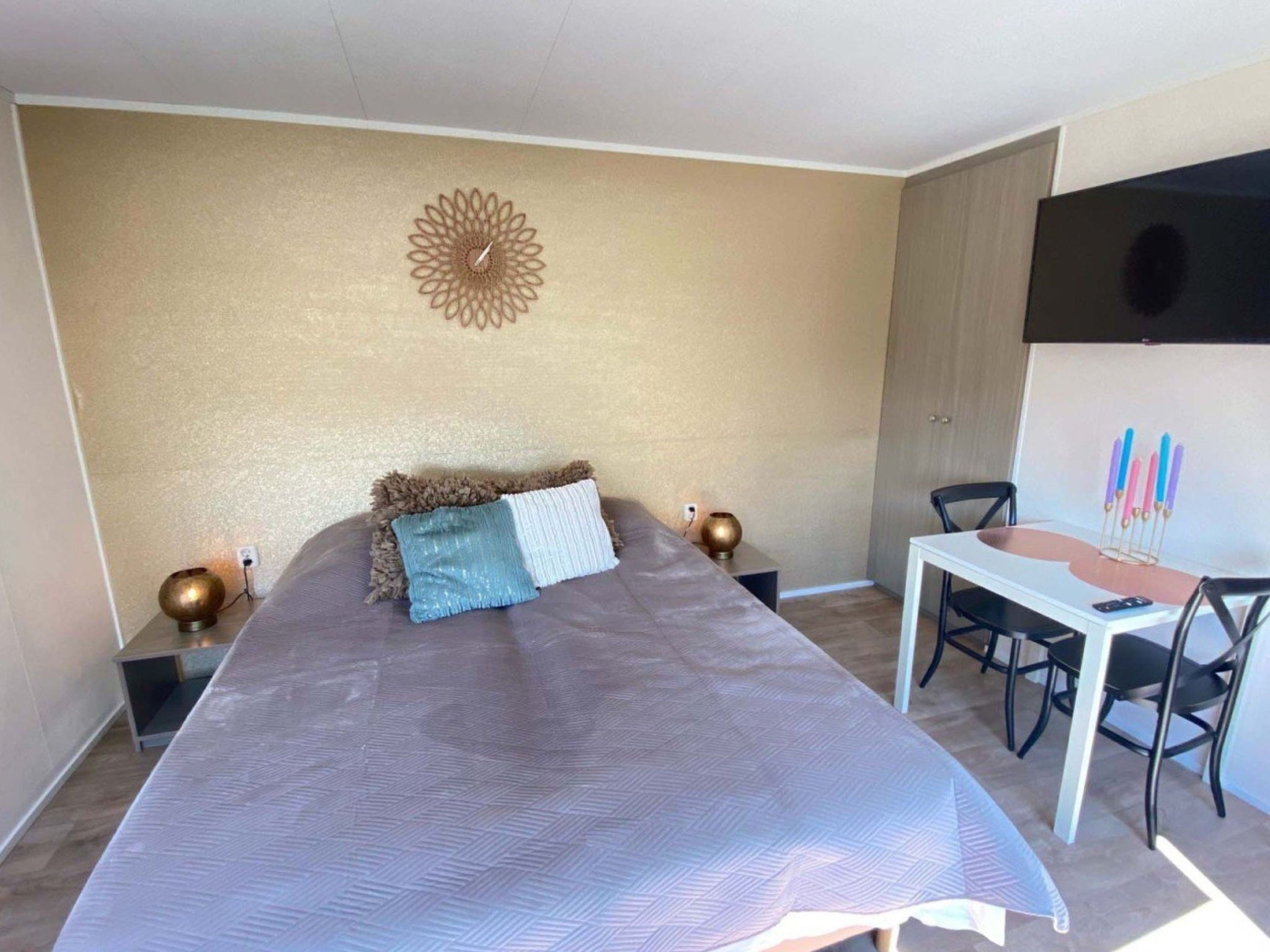 A bedroom with a bed, bedside tables, a desk, and a chair.